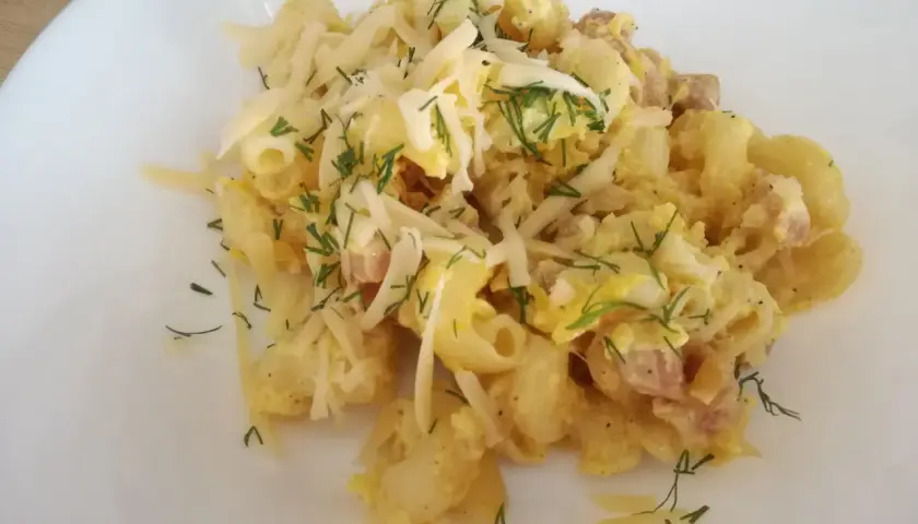 Pyszna carbonara z cukinią, makaronem, boczkiem i parmezanem, posypana świeżym koperkiem.