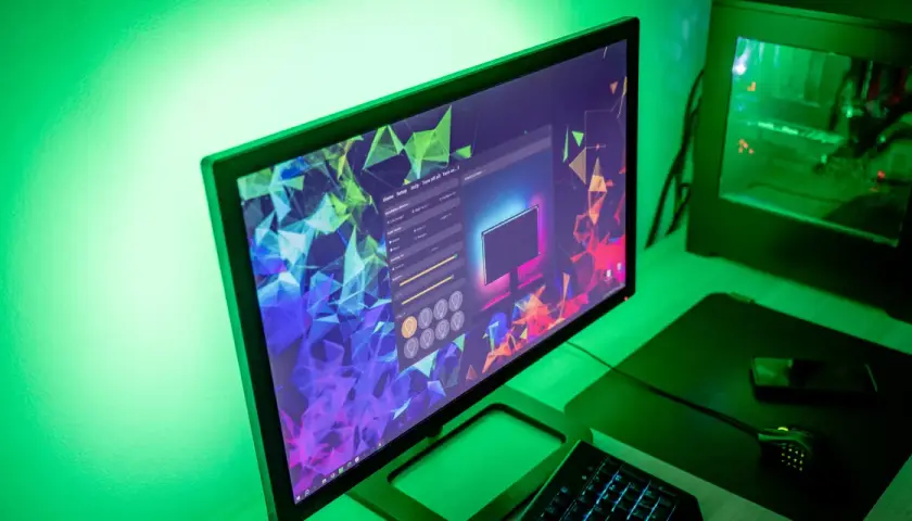 Komputer z podświetleniem w-led i led, tworzący zieloną poświatę. Na ekranie widać program do konfiguracji oświetlenia.