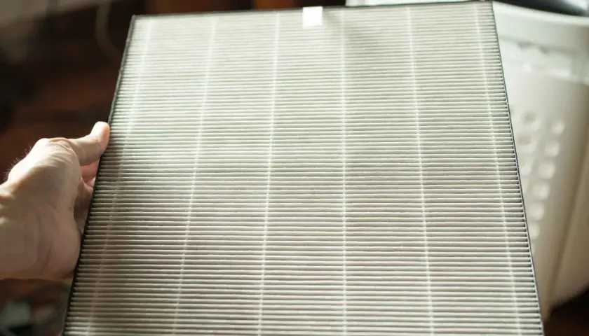 Mano sosteniendo un filtro HEPA. Si te preguntas como limpiar filtro HEPA no lavable, este es el tipo de filtro que debes reemplazar.