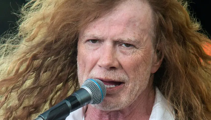 Dave Mustaine young, z burzą rudych włosów i mikrofonem przed ustami, śpiewa na scenie.