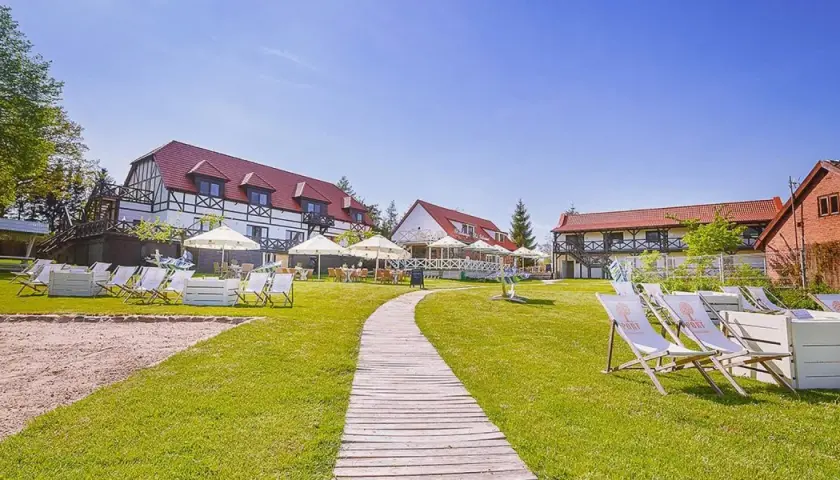 Słoneczny dzień na Mazurach. Urokliwe mazurskie miejscowości zapraszają do wypoczynku. Leżaki i parasole czekają na gości przy hotelu.