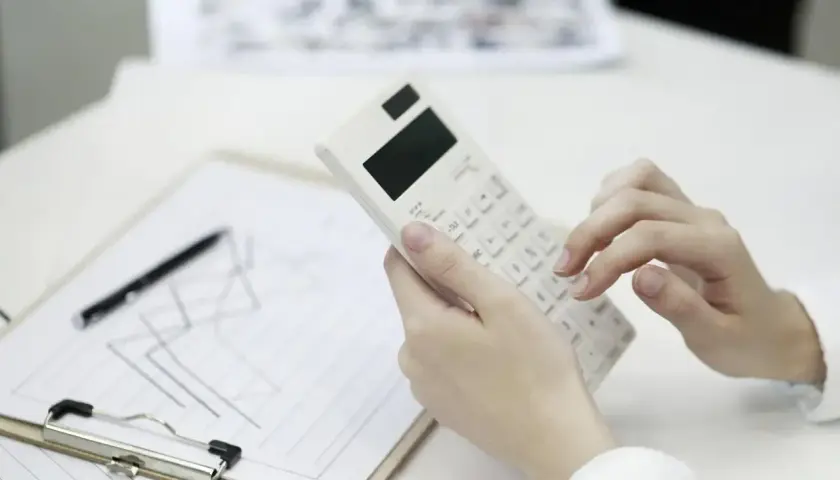 Ręce liczą na kalkulatorze, analizując wykresy. Warto sprawdzić, jak kredyt a inflacja wpływają na finanse.