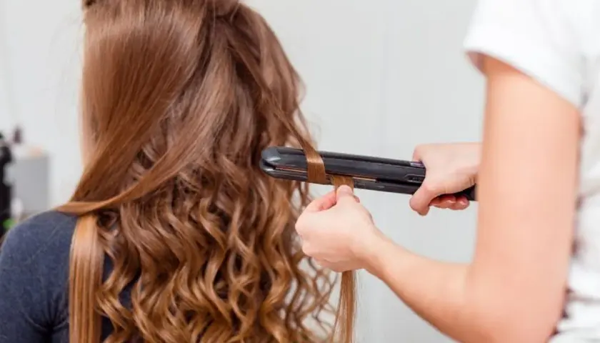 Creando ondas al agua con una plancha. El cabello castaño de una chica se riza, transformándose en suaves ondas.