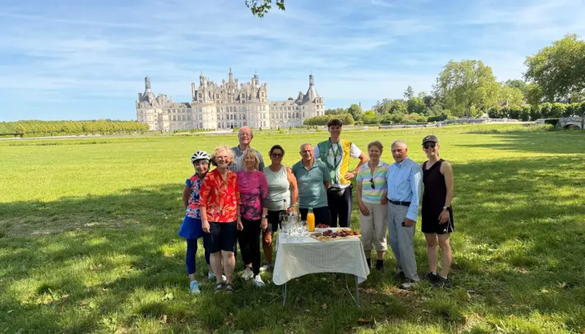 A group enjoys a picnic during their Loire Valley cycling tours, with the magnificent Château de Chambord in the background.