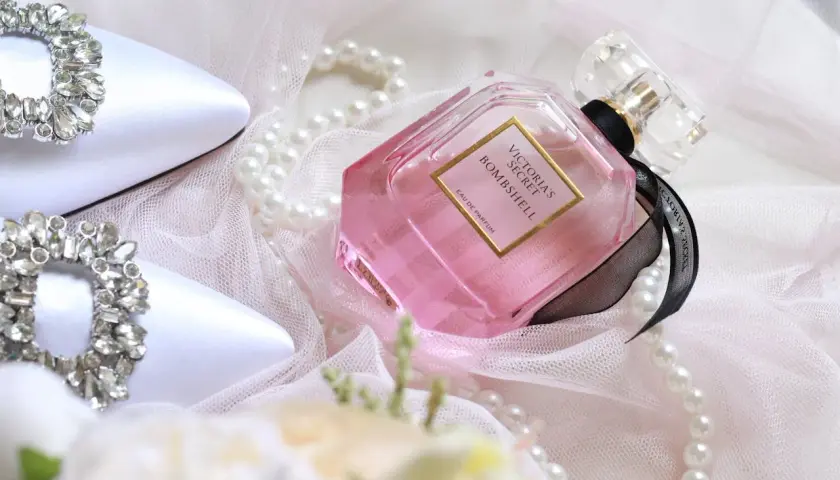 Eleganckie białe buty z kryształkami, różowe oznaczenia perfum Victoria's Secret Bombshell i perły na delikatnym tiulu.