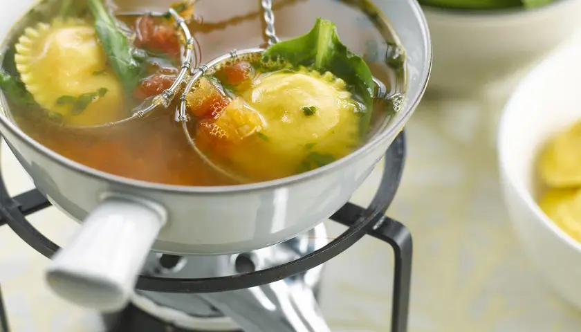 Raviolis dans un bouillon, accompagnés de légumes verts et de tomates. Une délicieuse fondue viande blanche à déguster.