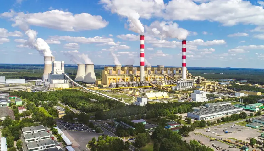 Ogromna elektrownia Bełchatów z kominami i chłodniami, emitująca białe kłęby pary. Zastanawiasz się, ile węgla spala elektrownia Bełchatów?