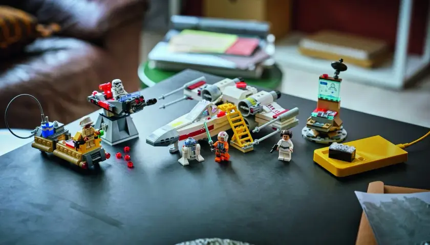 Lego Star Wars X-Wing mit Figuren und einem kleinen, smarten Lego brick auf einer gelben Ladestation.