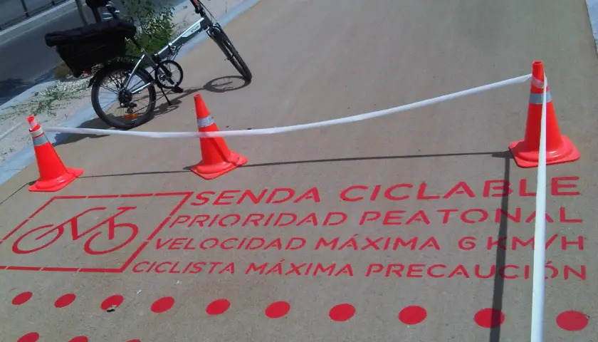 Bicicleta plegable en sendas ciclables con señalización de prioridad peatonal y límite de velocidad.