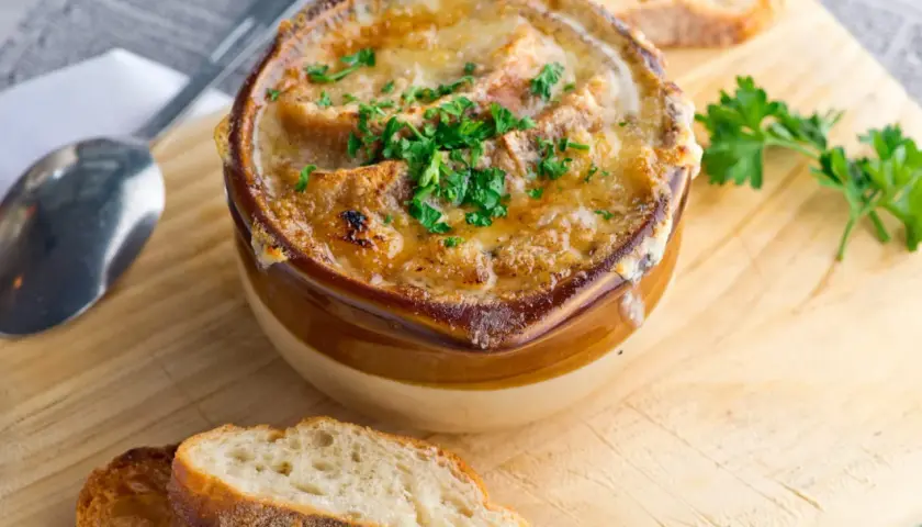 Soupe à l'oignon gratinée, un classique réconfortant. Croutons dorés, fromage fondu et persil frais. Parfait pour une recette maison.