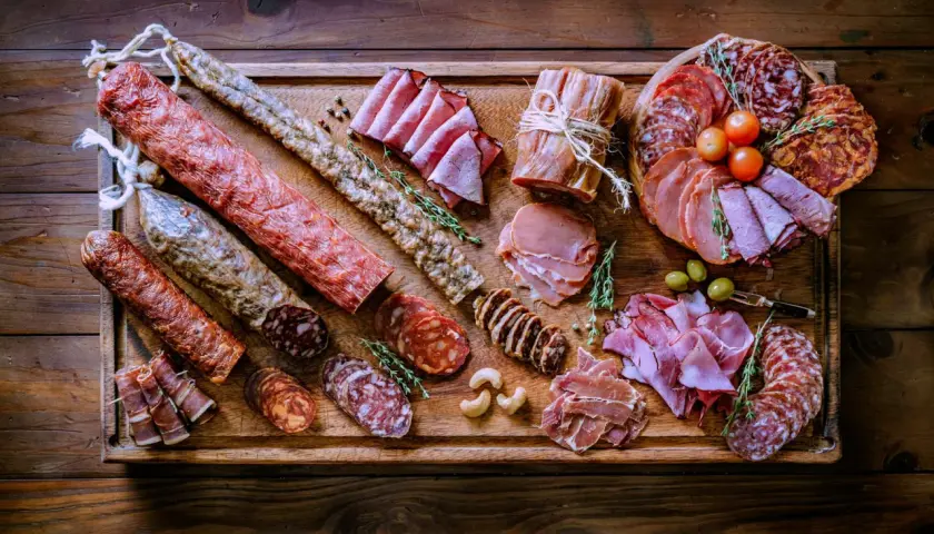 Bei taglieri di salumi e formaggi, un'abbondante selezione di prelibatezze italiane su un tagliere di legno rustico.