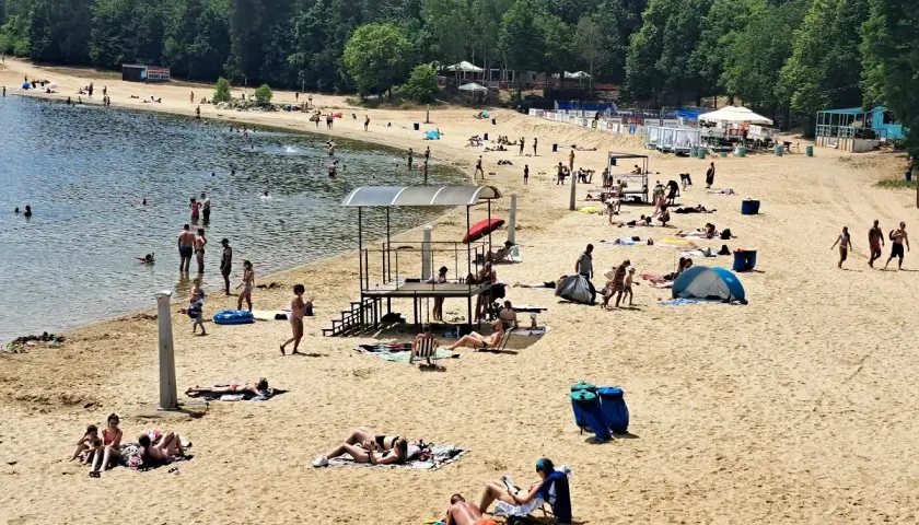 Słoneczna plaża Skorochów tętni życiem. Ludzie kąpią się, opalają i odpoczywają na piasku, ciesząc się letnim dniem.