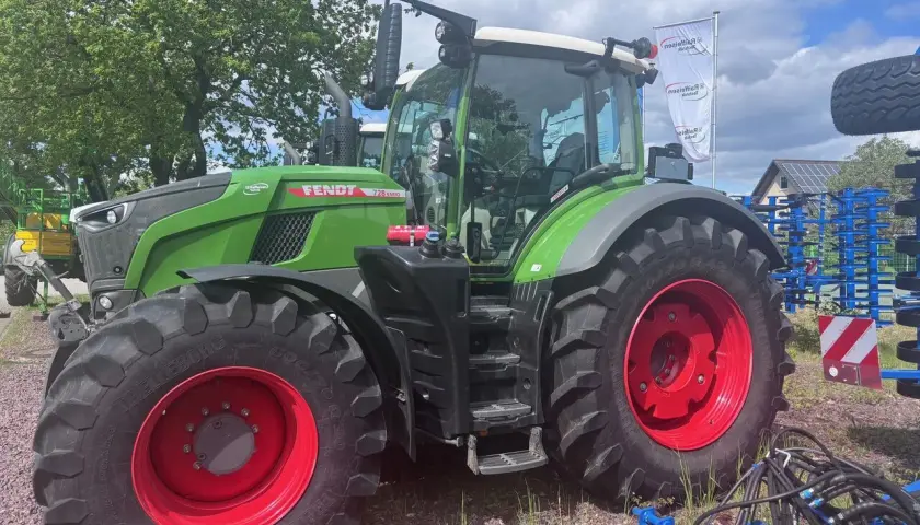 Zielony traktor Fendt 930 Vario z czerwonymi felgami, gotowy do pracy na polu.