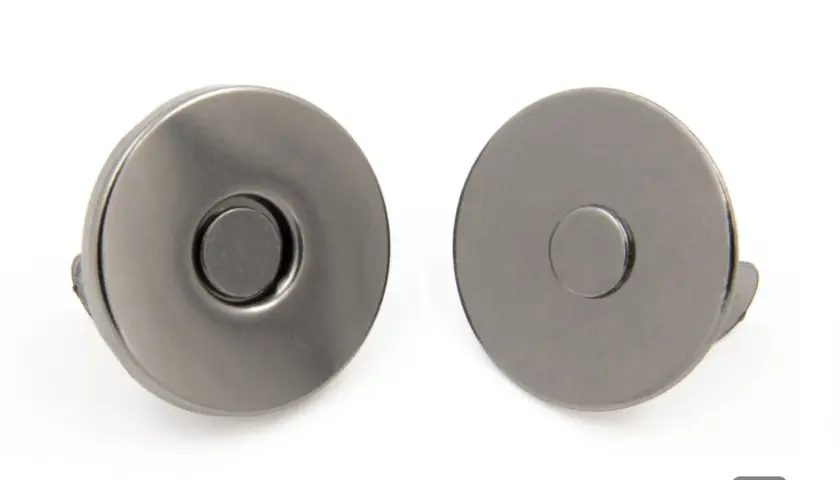 Dwa metalowe zatrzaski magnetyczne, niezbędne materiały kaletnicze do torebek i portfeli.