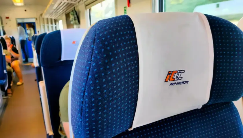 Wnętrze pociągu PKP Intercity. Siedzenia z zagłówkami, na których widnieje logo przewoźnika. Czy bilet PKP z rezerwacją miejsca czy bez – kiedy warto dopłacić?