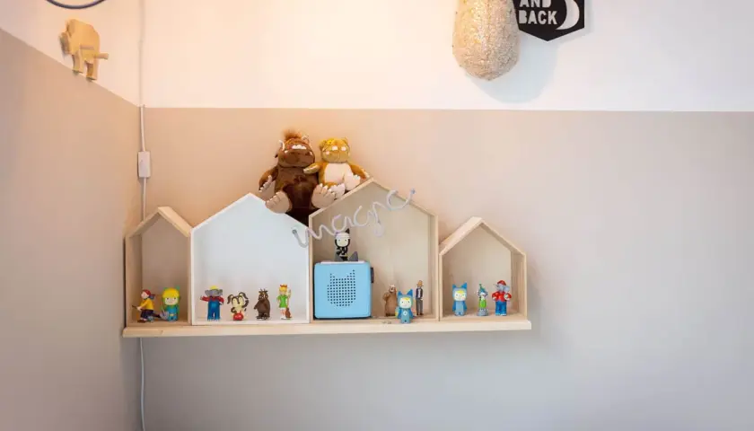 Ein selbstgemachtes Tonie Regal in Hausform, dekoriert mit Figuren und Stofftieren, schafft eine magische Spielzeugwelt.