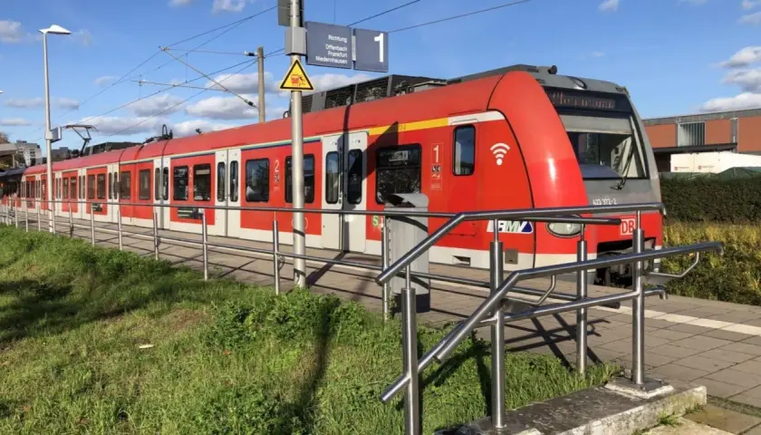 Rote S-Bahn am Bahnsteig. Informiert über den Kinderticket Preis für die Fahrt nach Offenbach, Frankfurt oder Niedernhausen.