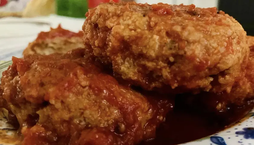 Polpette al sugo fumanti in una padella di ghisa, guarnite con prezzemolo fresco. Un classico confortante.
