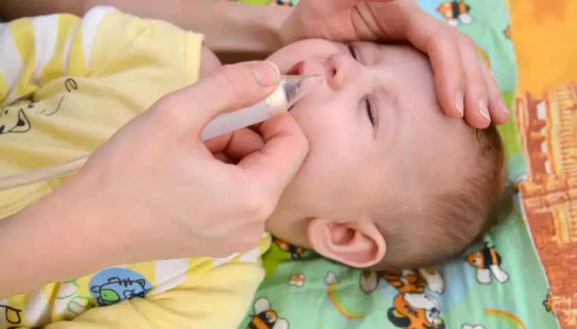 Mani delicate aiutano un neonato di 1 mese con il raffreddore, usando un aspiratore nasale per liberare il piccolo nasino.