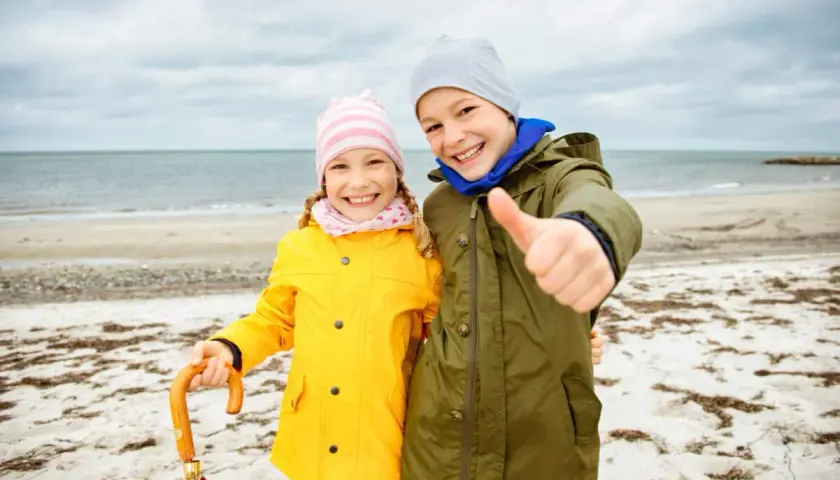 Zwei Kinder am Strand, bereit für Abenteuer, egal was kann man bei schlechtem Wetter machen.