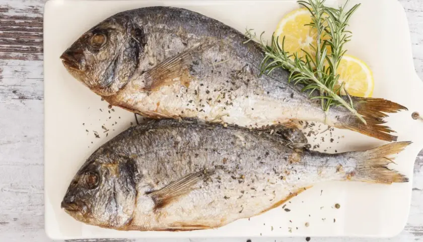 Zwei gebratene Doraden, garniert mit Zitrone und Rosmarin. Köstliche Fischarten zum Essen, bereit zum Genuss.