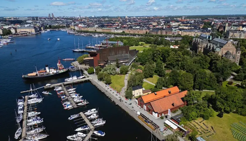 Stockholms hamn med många båtar och en byggnad som liknar Vin & Sprit Museet.