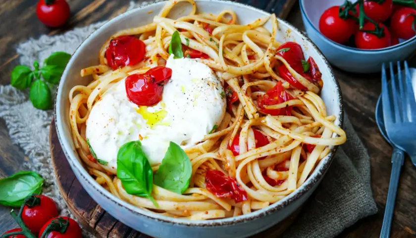 Spaghetti mit Burrata, Kirschtomaten und frischem Basilikum. Cremiger Käse schmilzt auf den Nudeln.