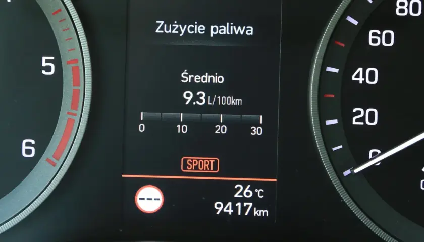 Na wyświetlaczu samochodu widać licznik spalania paliwa: średnie zużycie 9.3 L/100km. Obok widnieje tryb SPORT.