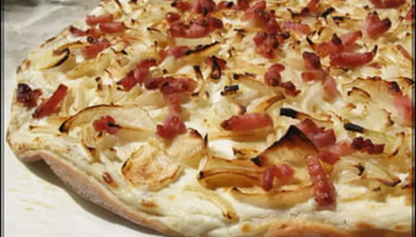 Flammekueche croustillante, garnie d'oignons et de lardons. Une recette simple et savoureuse pour un apéritif ou un repas léger.
