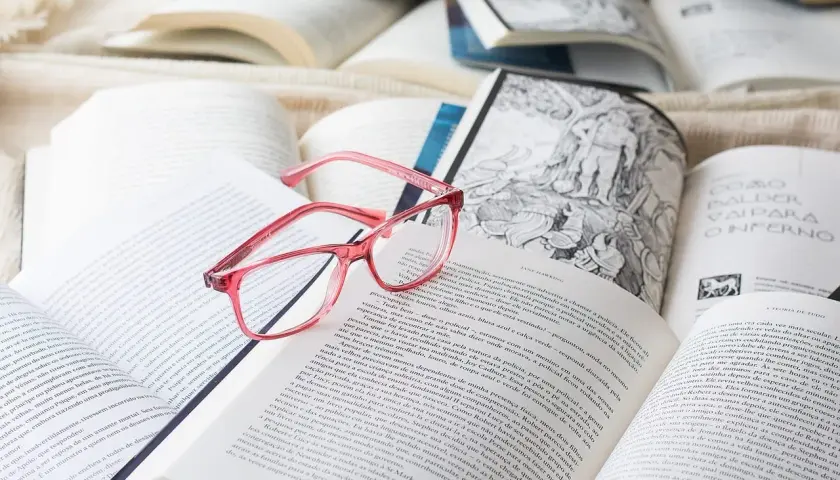 Różowe okulary leżą na otwartych książkach. Idealne do czytania po francusku, gdy tekst jest trudny.