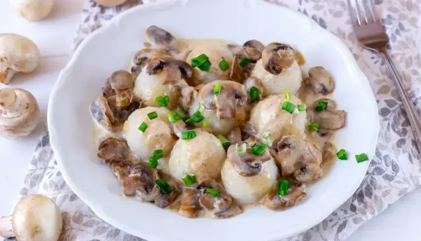 Pyszne kluski ziemniaczane w sosie pieczarkowym. Idealne, gdy zastanawiasz się, jak długo smażyć pieczarki, by były miękkie i aromatyczne.