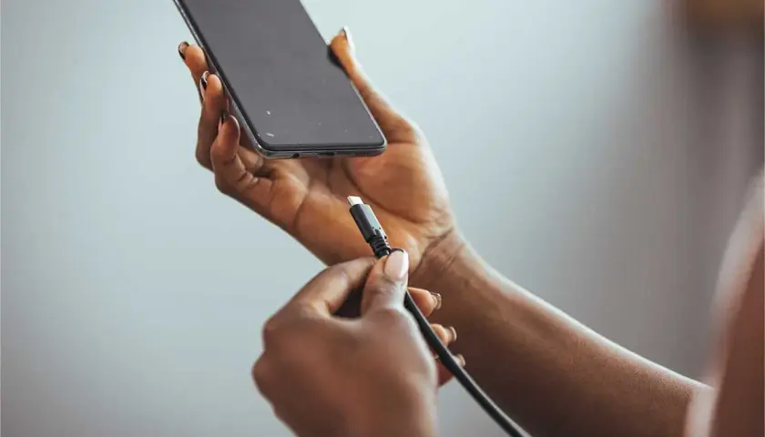 Dłoń z kablem USB przygotowuje się do podłączenia do telefonu, pokazując, jak naładować telefon telefonem.