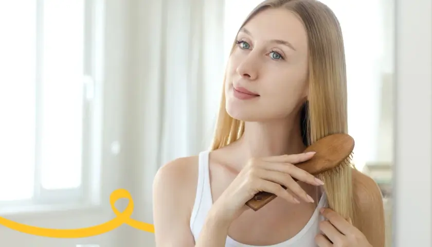 Kobieta szczotkuje włosy, przygotowując domowy peeling do skóry głowy.