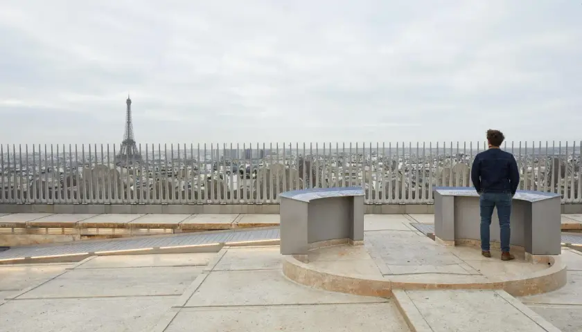 Widok na Paryż z platformy widokowej z wieżą Eiffla w tle i mężczyzną patrzącym na panoramę.