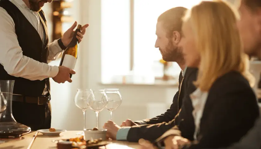 Ein Sommelier präsentiert eine Weinflasche. Die Bedeutung eines Sommeliers liegt in seiner Expertise für Wein und Speisen.
