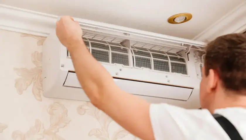 Technik sprawdza filtry klimatyzatora. Czy montaż klimatyzacji wymaga zgłoszenia? Zależy od przepisów.