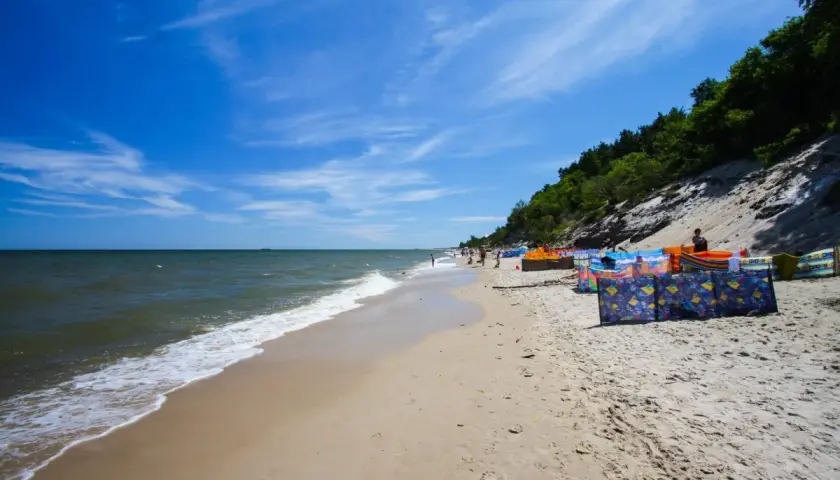 Słoneczna plaża w Chłapowie z kolorowymi parawanami, idealne miejsce na rodzinne wakacje i atrakcje dla dzieci.