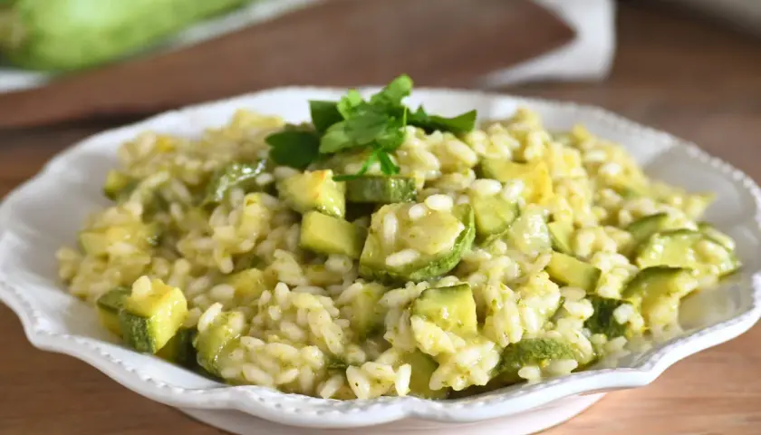 Un cremoso risotto con zucchine, guarnito con prezzemolo fresco. Un piatto estivo che profuma di casa.