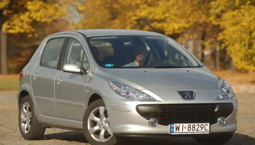 Srebrny Peugeot 307 na tle jesiennych drzew. Kierowca zastanawia się, jakie żarówki wybrać do swojego auta.
