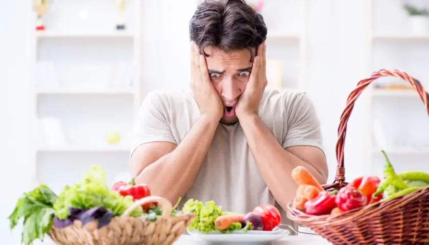 Uomo con espressione terrorizzata davanti a verdure fresche, simbolo di neofobia alimentare adulti.