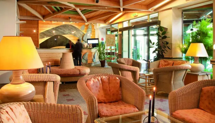 Lobby d'hôtel avec fauteuils en rotin, lampes et réception.