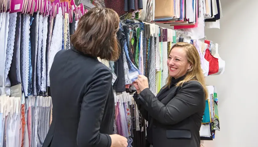 Deux femmes choisissent des échantillons de tissus, dont une belle dentelle en fibre artificielle, dans un atelier de mode.