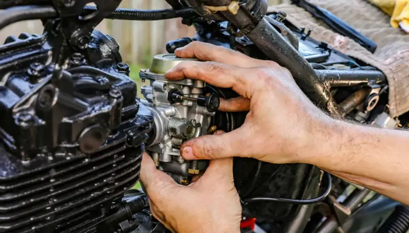 Manos ajustando el ahogador de moto, pieza clave para el arranque en frío.