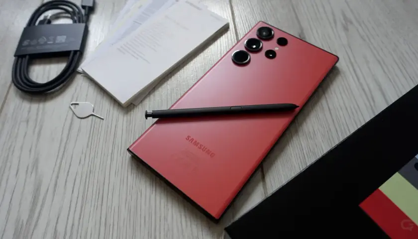 Czerwony Samsung S23 Ultra z rysikiem i akcesoriami. Aparat tego modelu pozwala na robienie niesamowitych zdjęć.