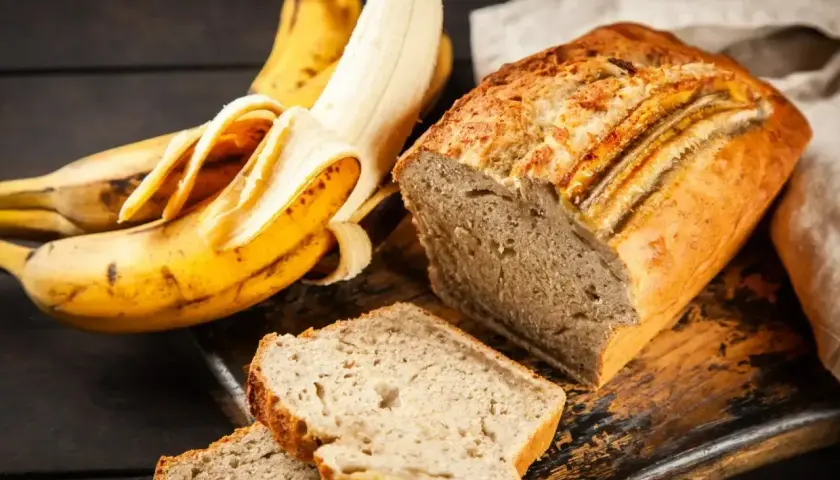Pyszne, wilgotne ciasto bananowe, które zawsze się udaje. Obok leżą dojrzałe banany, gotowe do pieczenia.