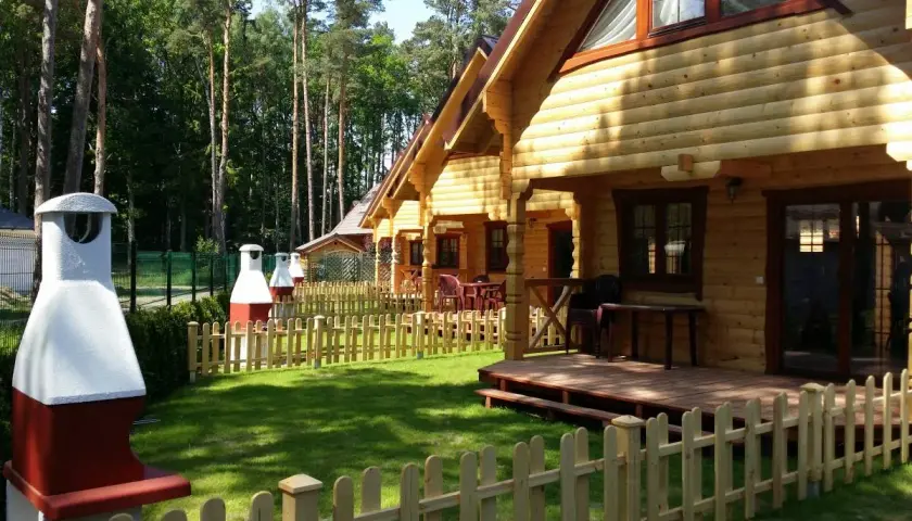 Drewniane domki nad morzem z psem czekają na gości. Piękny ogród i grill zachęcają do wypoczynku.