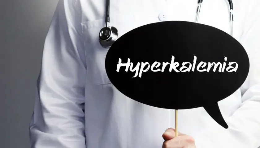Lekarz w białym fartuchu ze stetoskopem trzyma czarną chmurkę z napisem "Hyperkalemia".