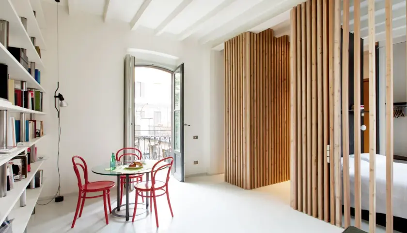Una moderna parete con listelli di legno fai da te divide lo spazio, creando un angolo lettura e una zona notte.