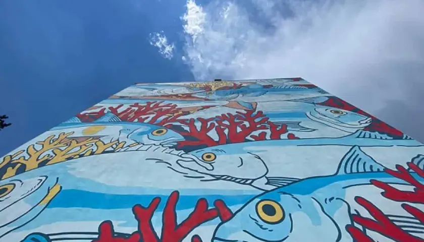Un'onda di colori subacquei decora un muro a Roma, un'esplosione di vita marina e coralli rossi. Roma street art che porta il mare in città.