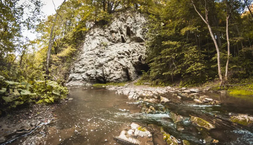 Grota w Rosolinie, znana jako jaskinia Jahybta, ukryta w skalnym zboczu, nad szumiącym potokiem.